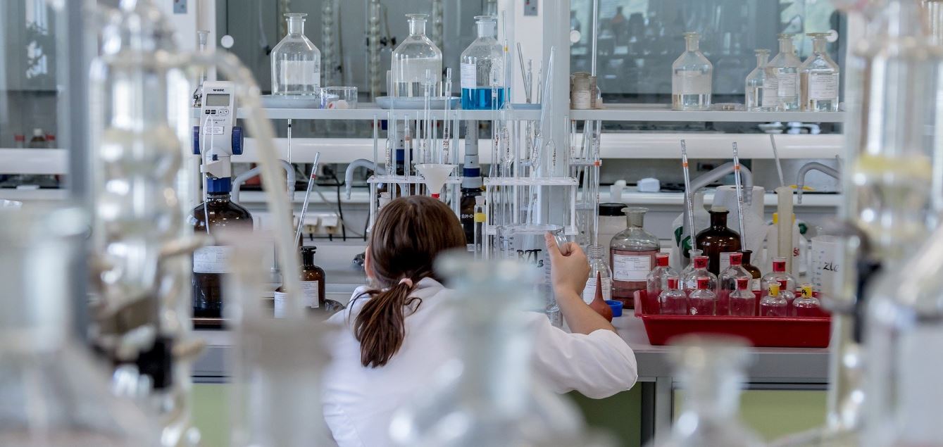 Researcher in lab using pipette Female researcher in lab, with back to camera using pipette