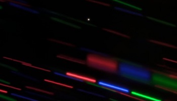 Minimoon (white dot) amidst stars coloured red, blue and green